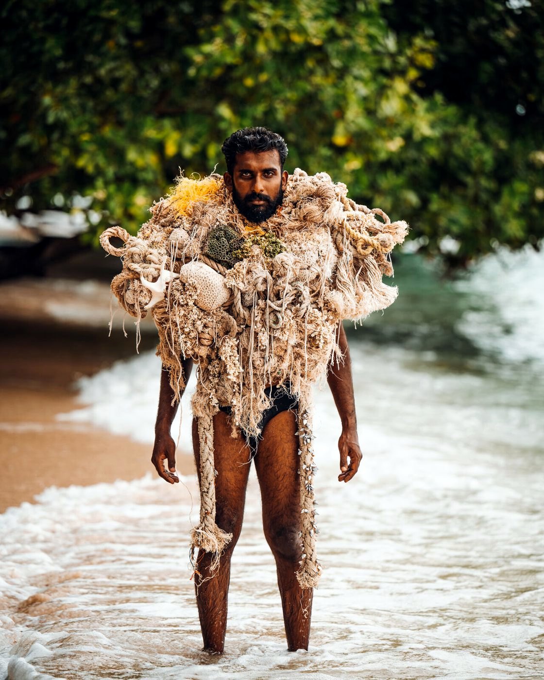 Diver at the shore in a costume of rope, shells and coral-like material