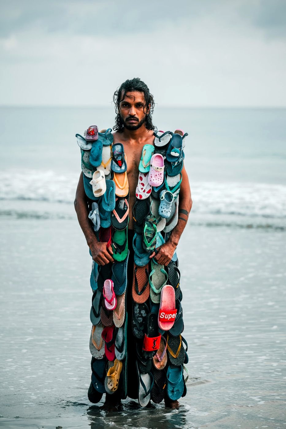 Diver standing in shallow water wearing a coat made of flip-flops